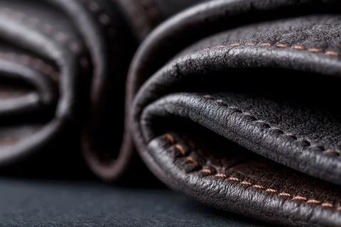 Two rolled leather pieces on a dark surface in a close-up shot showing stit.. 스톡 사진