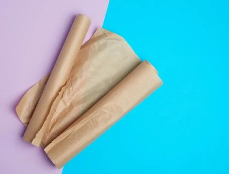 Two rolled rolls of brown parchment baking paper on a colored background Stock Photos