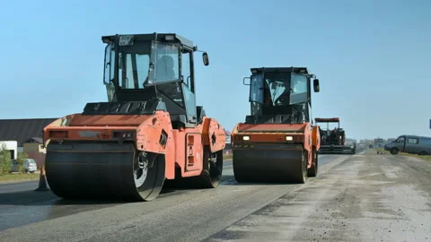 Two rollers level and compact the asphalt against the blue sky. Road rollers 库存影片 141054492