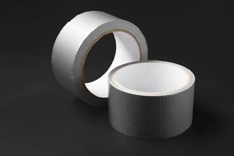Two rolls of gray duct tape on a dark background, industrial repair and const Stock Photos