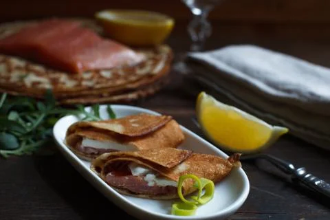 Two rolls of thin wheat pancake with salmon and soft cheese, served with lemo Stock Photos