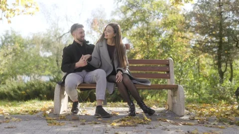 Two romantic lovers sitting on a park bench holding hands in cinematic style. Stock Footage 332764032