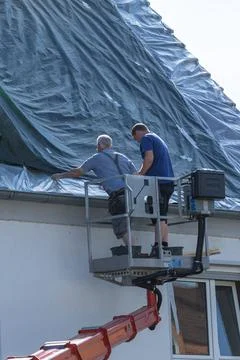 Two roofers on an elevating pla Stock Photos