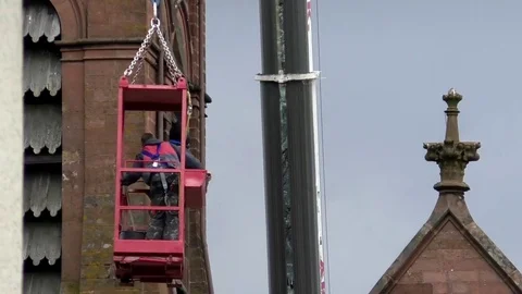 Two roofers in man basket moved through air by crane, church maintenance Stock Footage 82738587