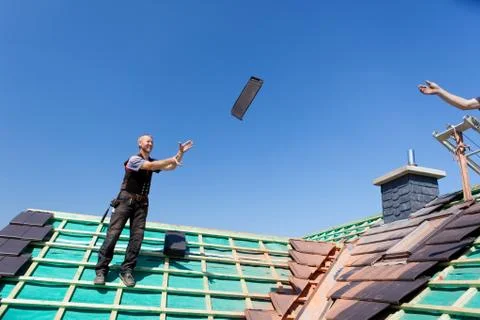 Two roofers tossing tiles Stock Photos