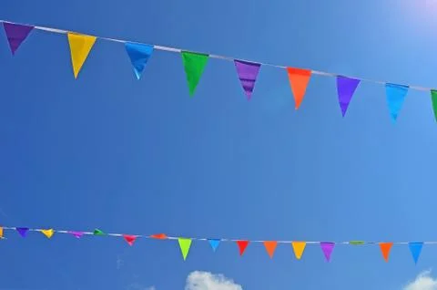 Two rope with colored flags hanging on a blue sky background Stock Photos