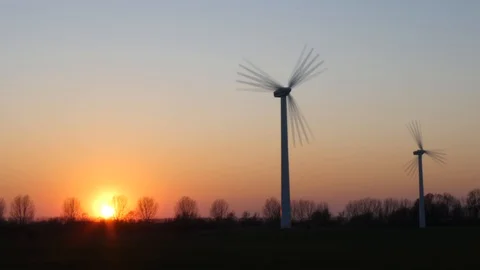 Two rotating wind turbines with setting sun on a wintry meadow - time lapse Stock Footage 106536483