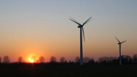 Two rotating wind turbines with setting sun on a wintry meadow - slow motion Stock Footage 106546707