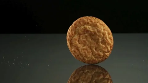 Two round cookies rolling across a dark reflective surface Stock Footage 327632108