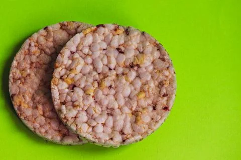 Two round crispbreads with small grains close-up on a green background. Stock Photos