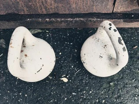 Two round dumbbells with handles painted in white paint are standing on the Stock Photos