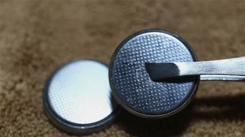 Two round silver batteries close-up, on a brown background, real time. Hold one Stock Footage 149211472
