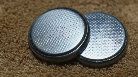 Two round silver batteries close-up, on a brown background, real time, camera mo Stock Footage 149211623
