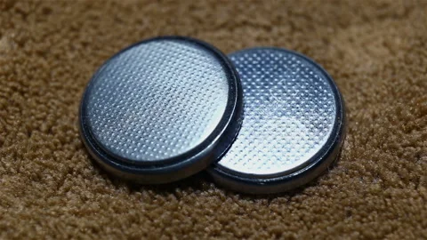 Two round silver batteries close-up, on a brown background, real time Stock Footage 149211810