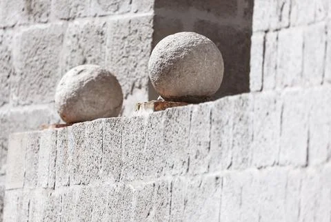 Two round stone spheres rest on a stepped brick wall Stock Photos