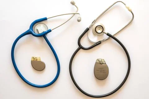 Two rounded stethoscopes with a pacemaker battery in the center with white ba Stock Photos