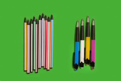 Two row of of colored pens lying on a green background Stock Photos