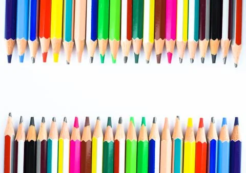 Two rows of different colored wax crayons arranged facing each other on a whi Stock Photos