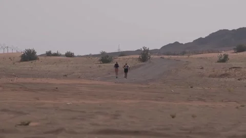 Two runners in the desert on a cloudy day. Stock Footage 248300735