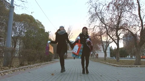 Two running girlfriends with shopping. Stockbeeldmateriaal 82099614