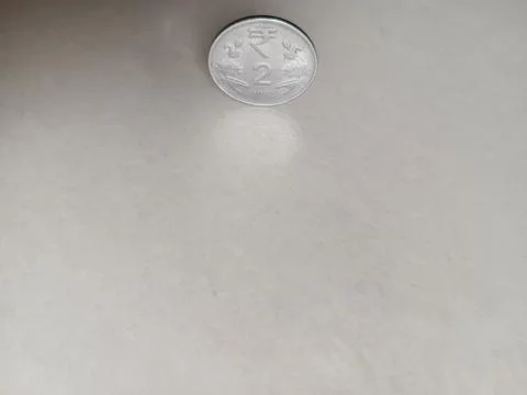 Two rupees coin with its shadow. light brown background for financial matter Stock Photos