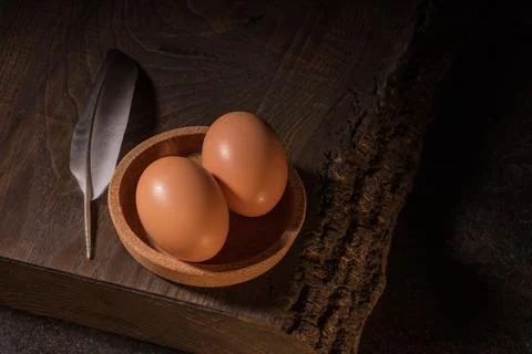 Two rustic chicken eggs resting on a dark wooden table, adorned with a delica Stock Photos