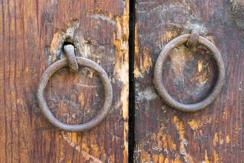Two rusty iron ring door knobs over an old wooden door Fotos de archivo