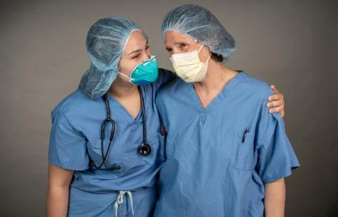 Two sad nurses consoling each other outside the OR. Stock Photos