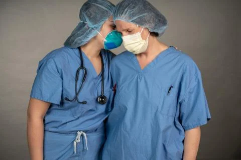 Two sad nurses consoling each other outside the OR. Stock Photos