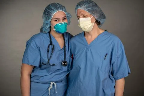 Two sad nurses consoling each other outside the OR. Stock Photos