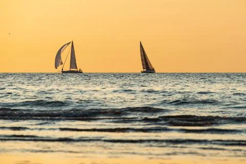Two sailing boats navigating at sunset Stock Photos