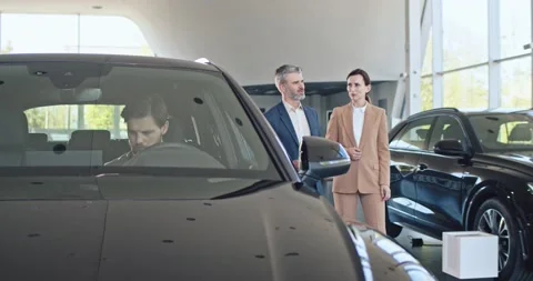 Two sales managers are talking to each other in car showroom. Smiling caucasian Stock Footage 156542834