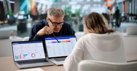Two Sales Managers Discuss CRM Software Features On Laptop For Business Growt 写真素材
