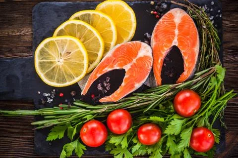 Two salmon steakes with greenery, lemon and cherry tomatoes on the black boar Stock Photos