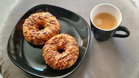 Two Salted Caramel Donuts with Chopped Nuts and Mug of Coffee 스톡 사진