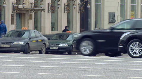 Two Same Black Cars go on the Road in the City, People go Through the Stock Footage 65405958