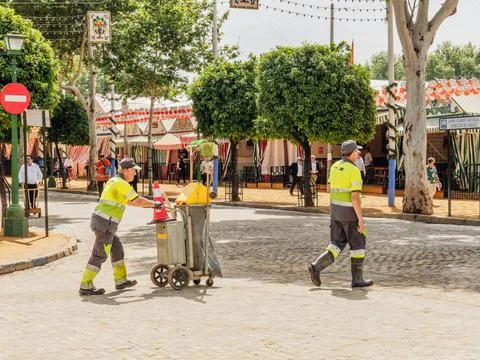 Two sanitation workers in high-visibility uniforms clean the streets during the Stock Photos