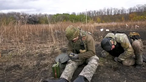 Two sappers are sitting on the ground. The ammunition is detonated remotely Video stock 256627960