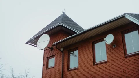 Two satellite TV antennas on the facade of a private red brick house with a soft Stock Footage 220632464