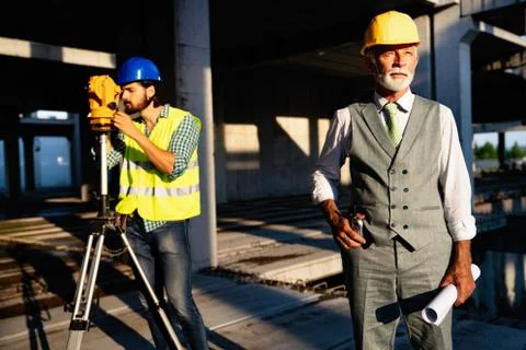 Two satisfied engineers talking at building site with construction structure in Fotos de archivo
