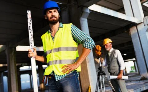Two satisfied engineers talking at building site with construction structure in Fotos de archivo