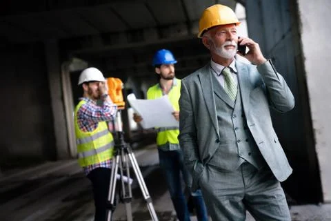Two satisfied engineers talking at building site with construction structure in Fotos de archivo