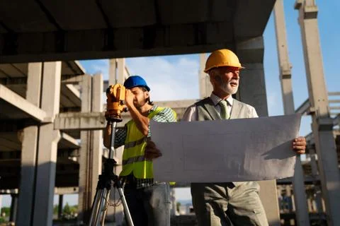 Two satisfied engineers talking at building site with construction structure in Fotos de archivo