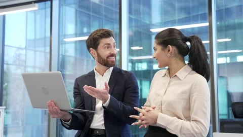 Two satisfied happy co-workers celebrate success at work using laptop. Smiling  Stock Footage 298998176