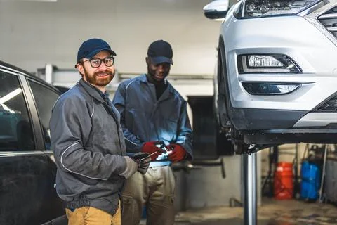 Two satisfied mechanics working in the workshop and smiling, love your job Stock Photos