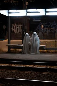 Two scary ghosts sitting at stop outdoors at night 스톡 사진