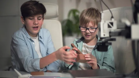 Two school boys are actively discussing the parts just printed on the 3D printer Stock Footage 335376093