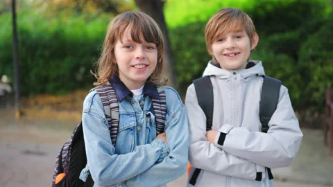 Two school boys with backpacks smiling outdoors as school kids head to class. Stock Footage 338139552