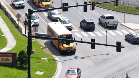 Two school buses lead queued traffic at busy Lynchburg intersection, rows of Stock Footage 345700391