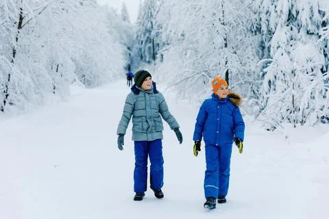 Two school kid boy walking in snowy winter forest. Happy children having fun Stock Photos
